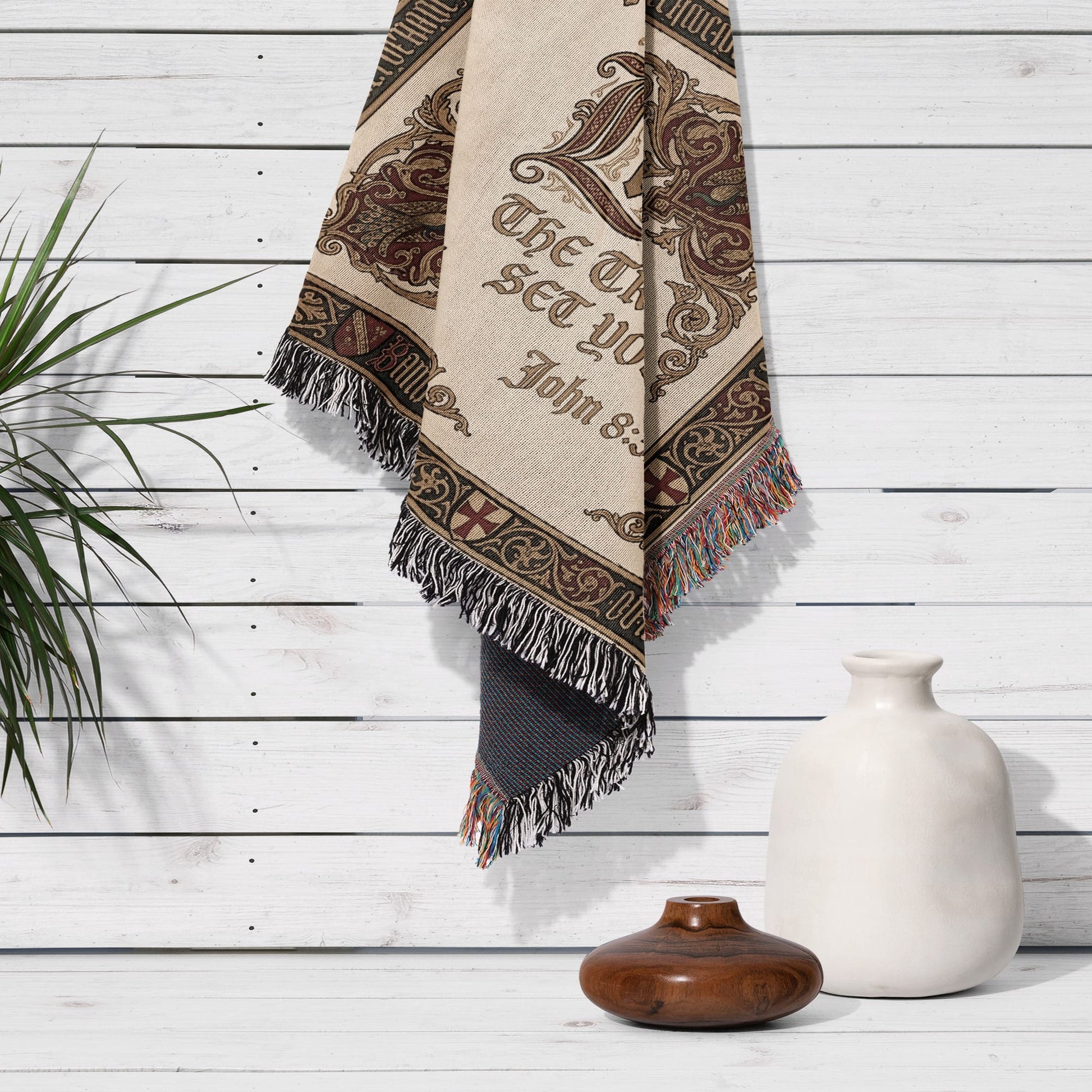 Woven blanket with "The Lord Set You John 8:32" text hanging on a white wooden wall.