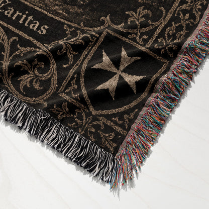 Black blanket with Maltese cross and ornate scrollwork, fringed edge.