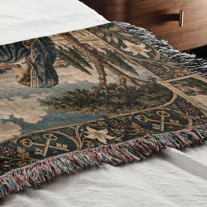 Woven throw blanket featuring a classic tapestry design with figures, trees, and decorative fringe.