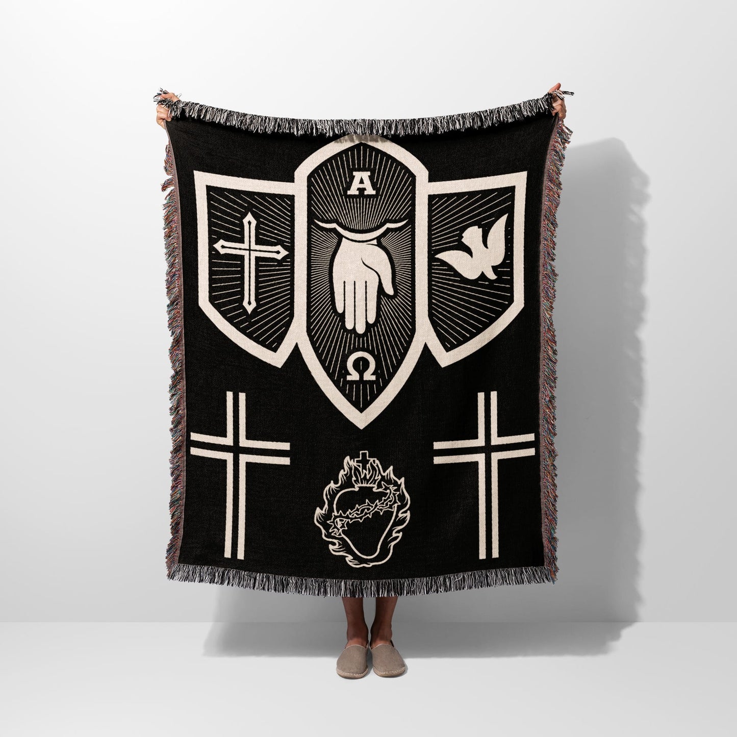 Black tapestry blanket with religious symbols: hand, dove, crosses, and heart.