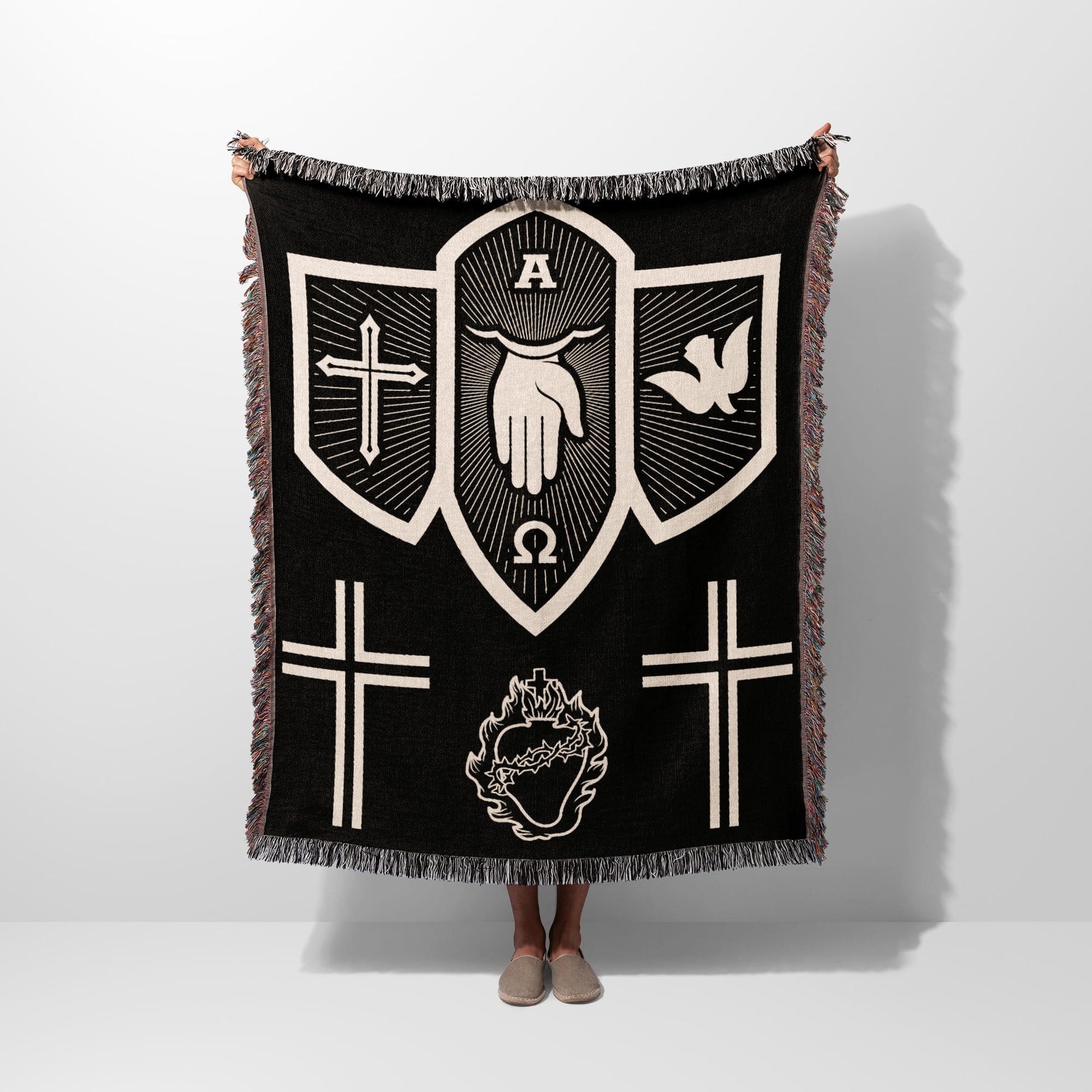 Black tapestry blanket with religious symbols: hand, dove, crosses, and heart.