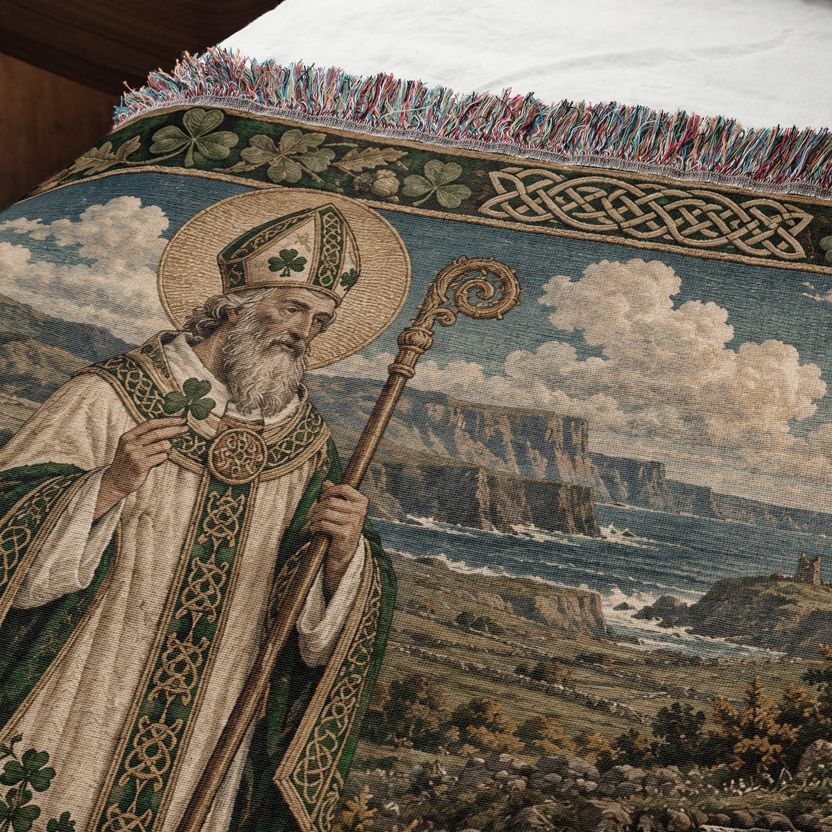 Woven tapestry throw blanket featuring Saint Patrick against a coastal landscape background with a decorative border.