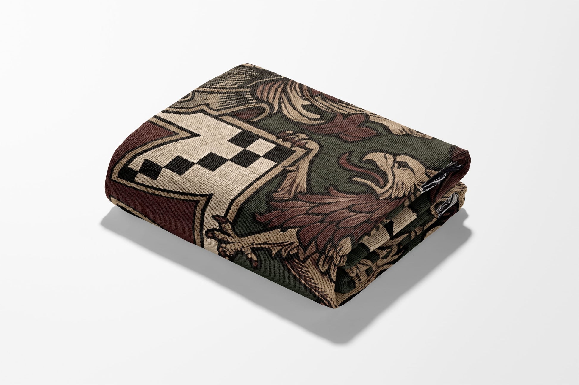 Folded blanket with a dark green background and a tapestry-style crest design.