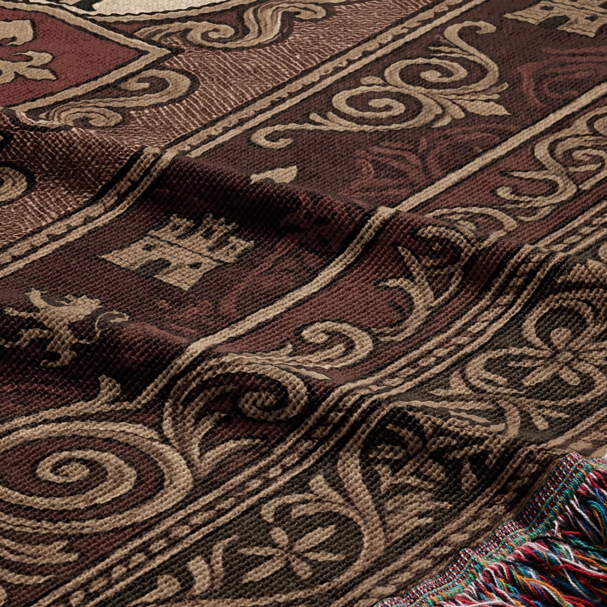 Brown throw blanket with ornate paisley and crown patterns and colorful fringed edge.
