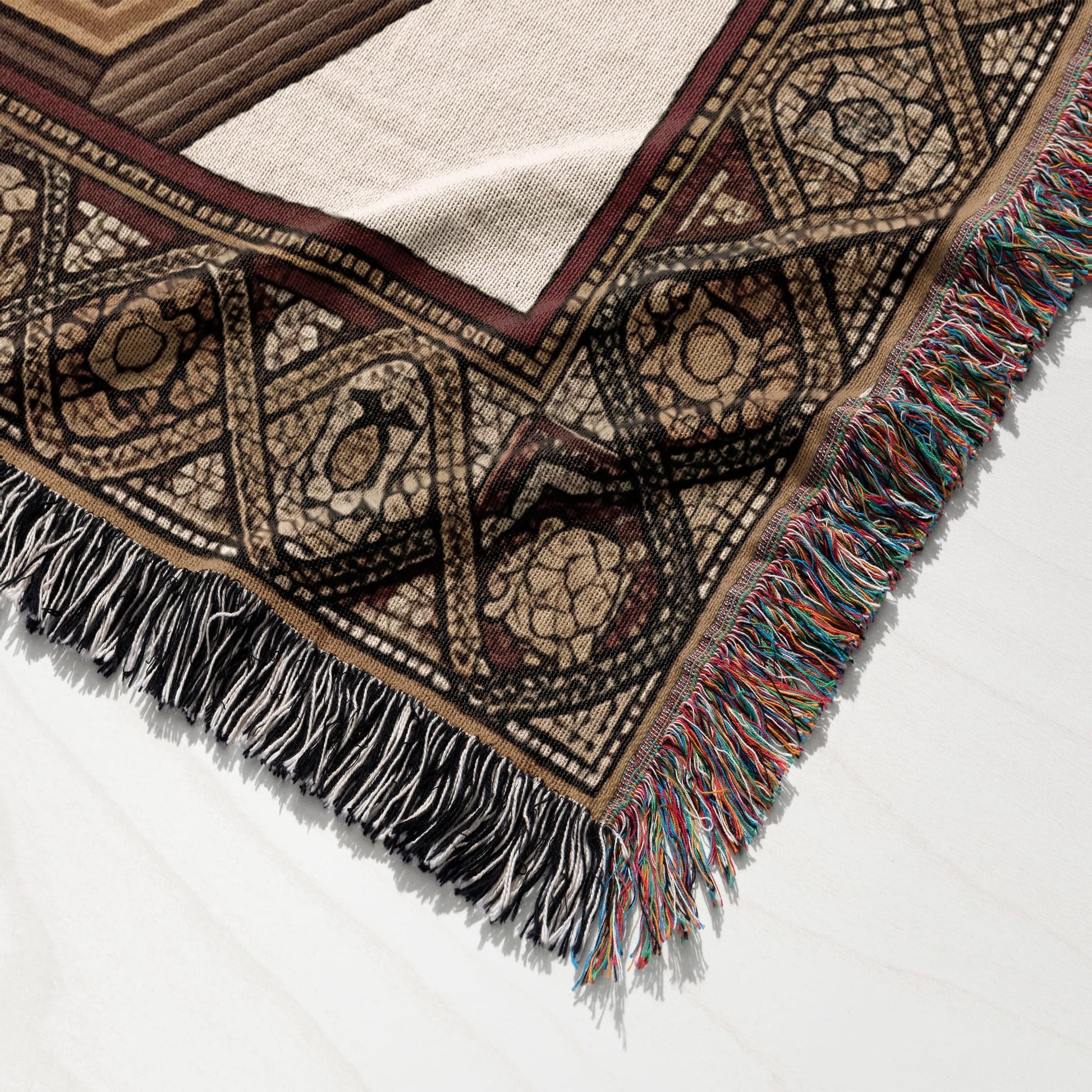 Woven blanket with geometric patterns and tasseled fringe.