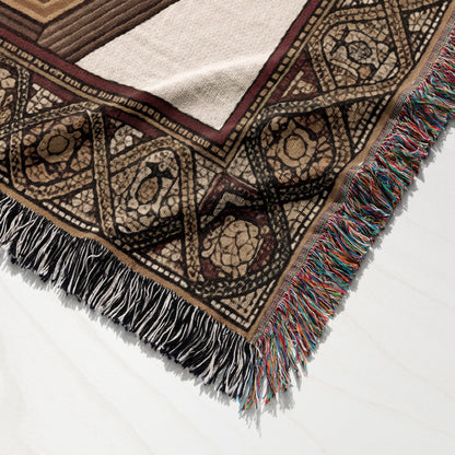 Woven blanket with geometric patterns and tasseled fringe.