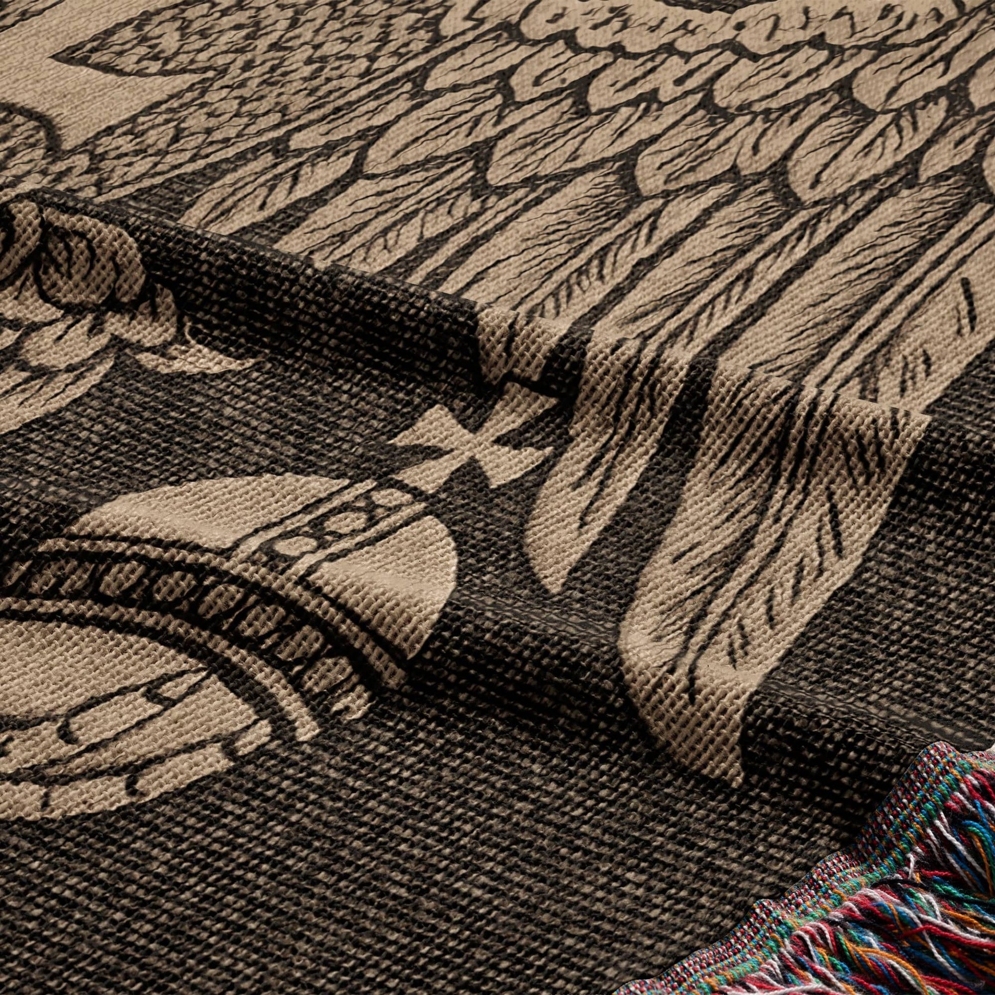 Woven blanket with large eagle wings and ornate emblem, fringed edge.