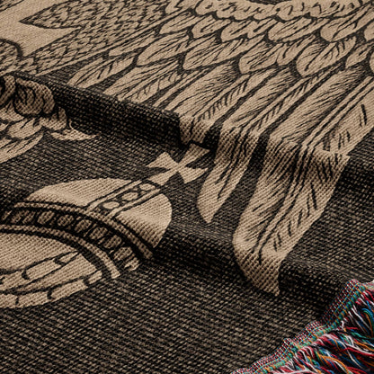 Woven blanket with large eagle wings and ornate emblem, fringed edge.