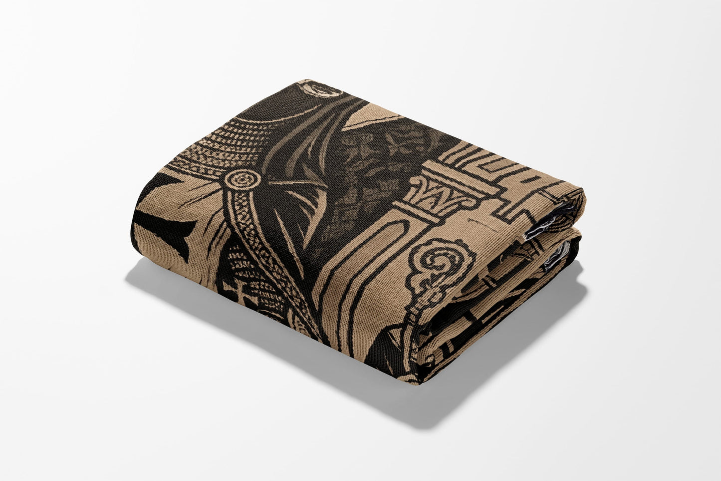 Folded tan blanket with black tribal-style pattern featuring columns and ornate details.