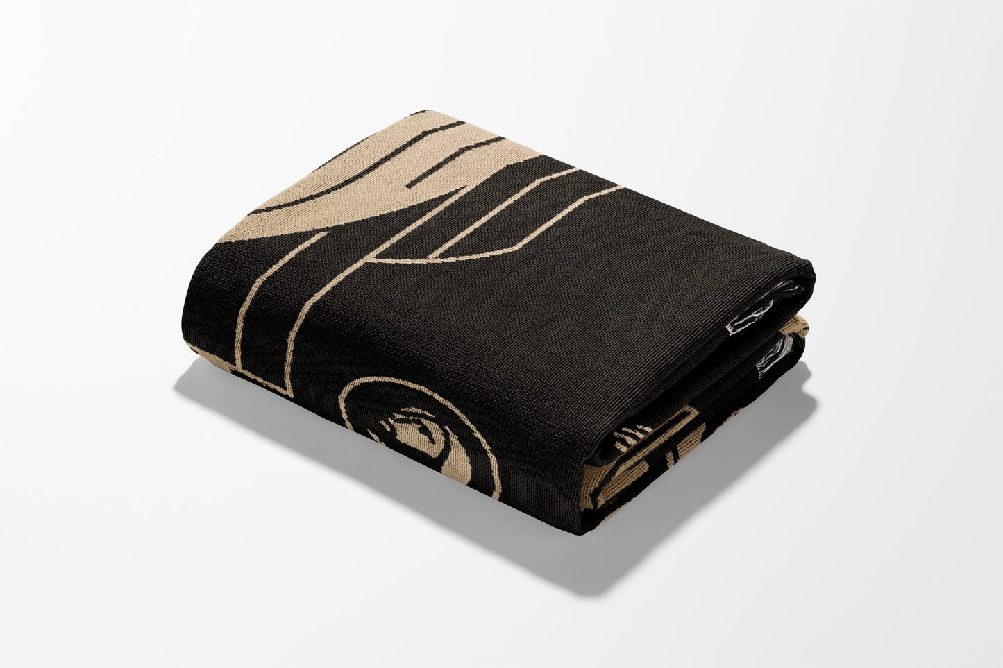 Black blanket with tan geometric pattern, folded on a white background.