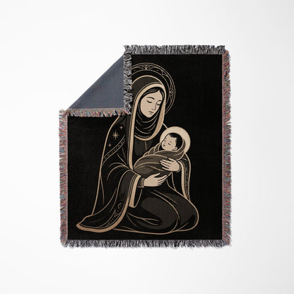 Black woven blanket with fringed edges featuring Mary holding baby Jesus.