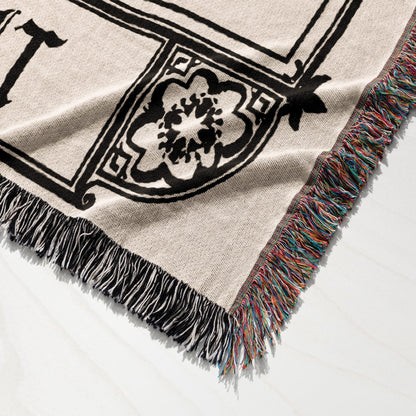 Woven blanket with black tribal pattern and colorful fringe.