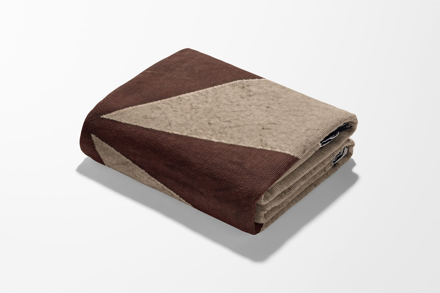 Folded brown and tan geometric patterned blanket on a white background.