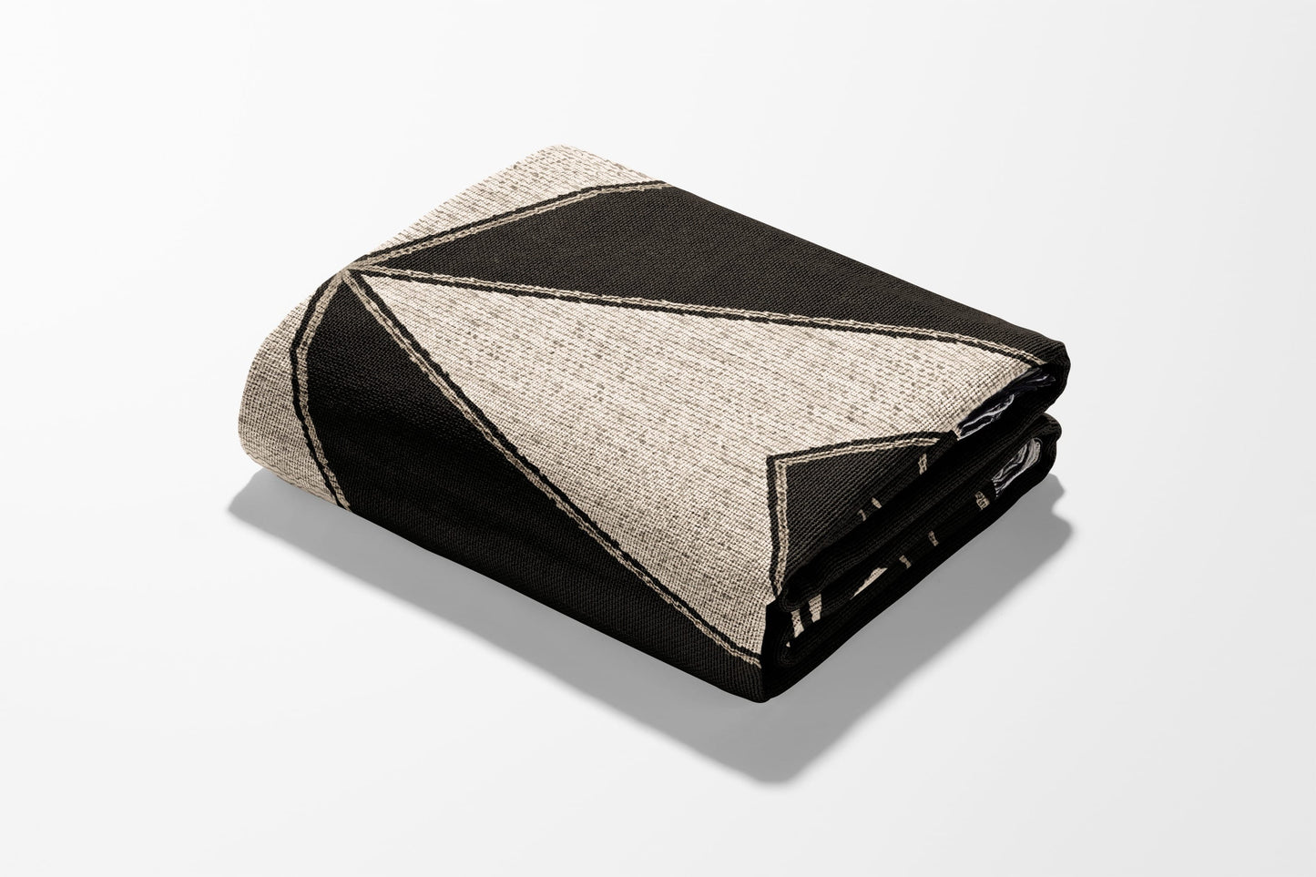 Folded blanket with geometric black and tan pattern against white background.