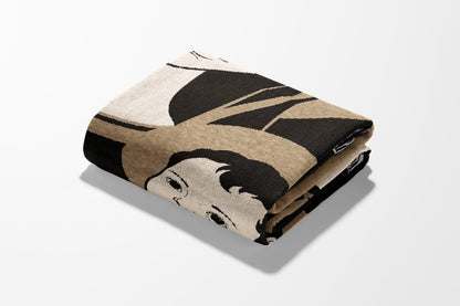 Folded blanket with a stylized black and white portrait pattern.