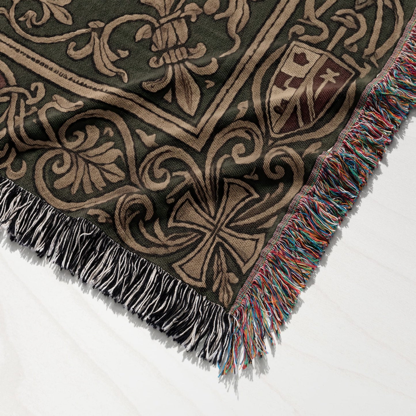 Green and tan woven throw blanket with fringe, featuring floral and crest designs.