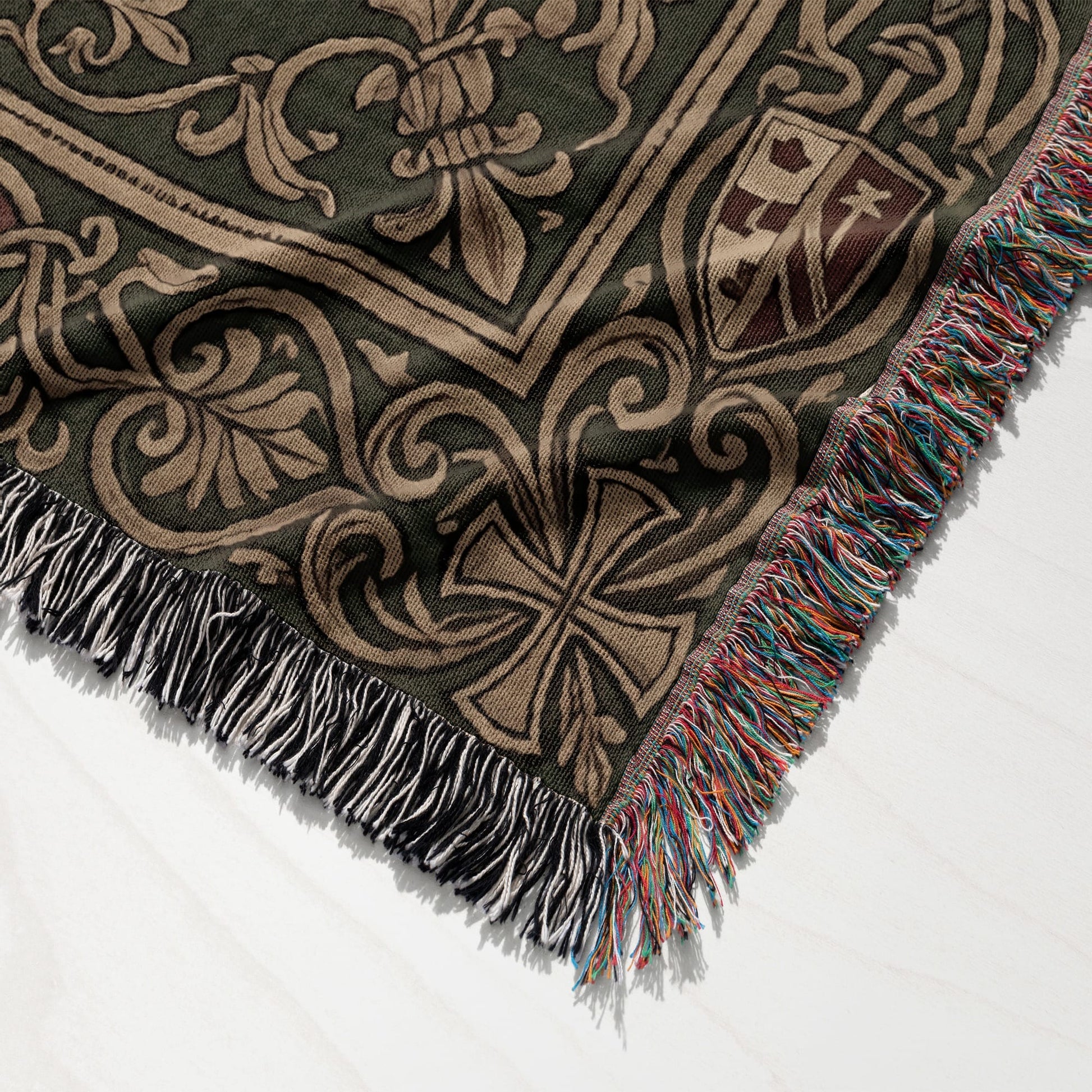 Green and tan woven throw blanket with fringe, featuring floral and crest designs.