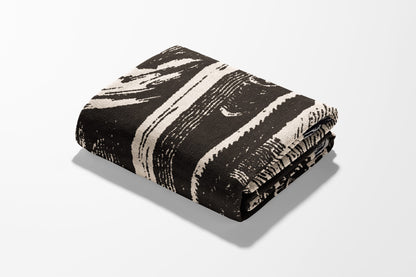 Folded blanket with abstract black and white stripe pattern.