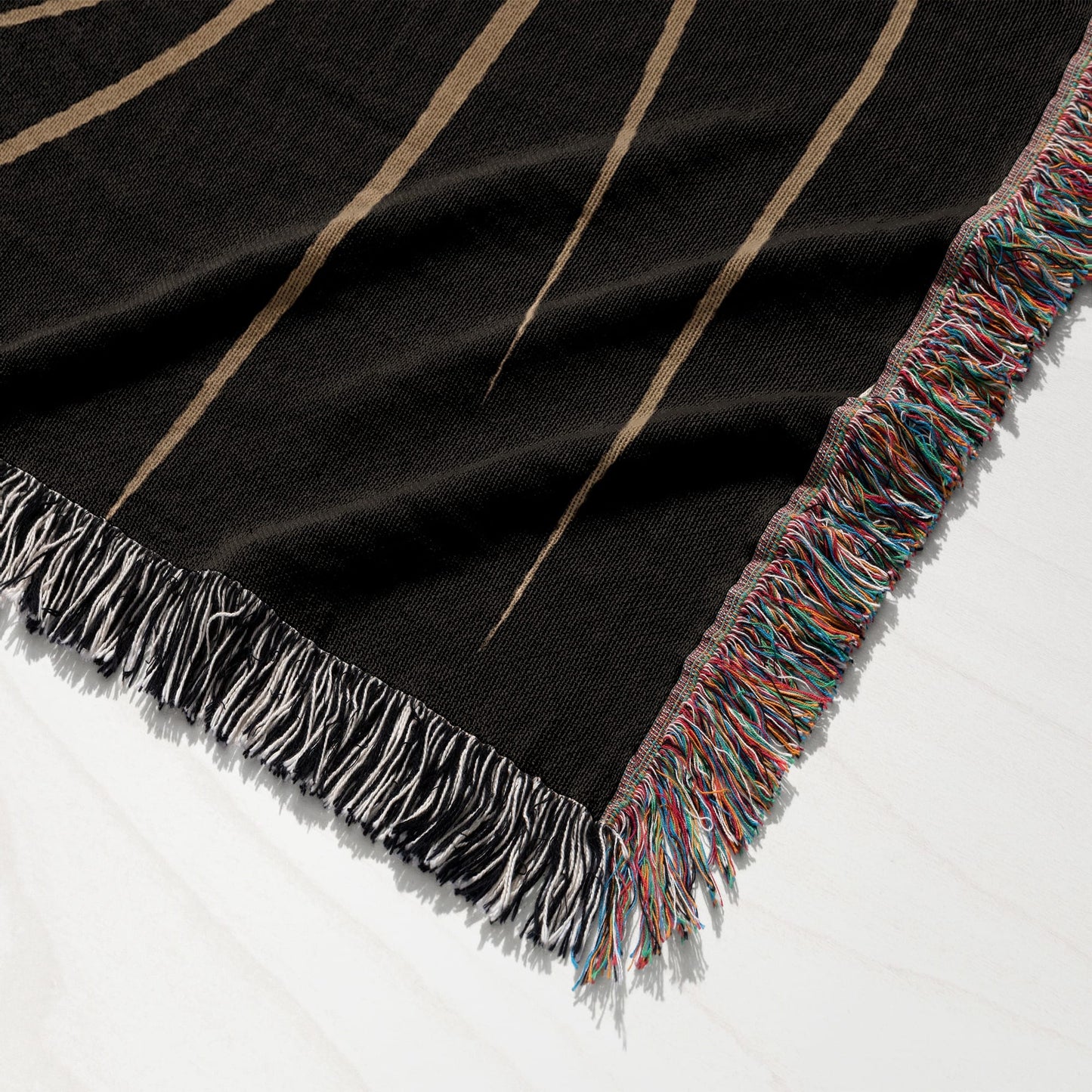 Black woven throw blanket with fringe and sunburst pattern.