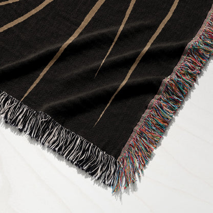 Black woven throw blanket with fringe and sunburst pattern.