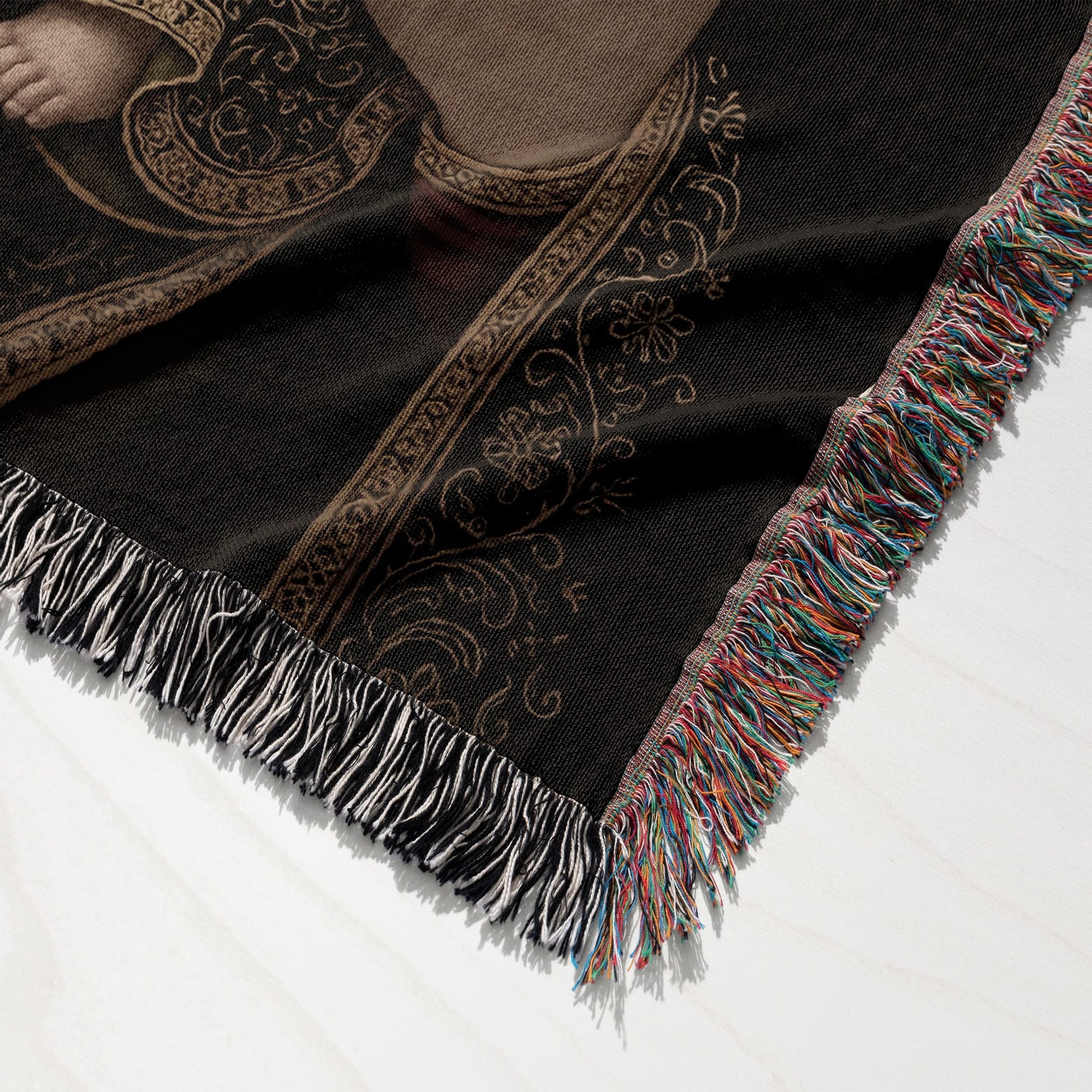 Black woven blanket with fringe and ornate gold pattern.