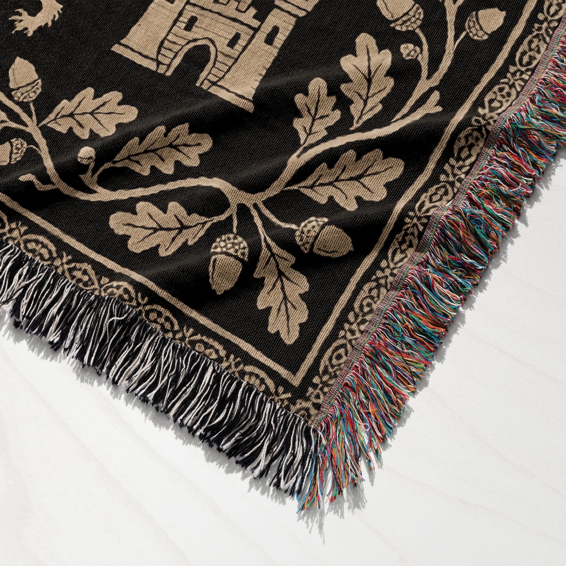 Woven blanket with castle and oak leaf design, fringed edges.