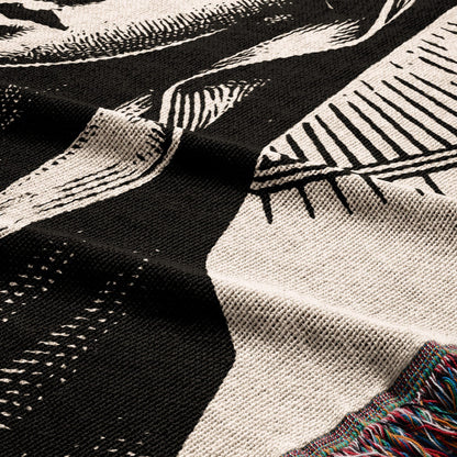 Close-up of a black and white knit blanket with colorful fringe detail.