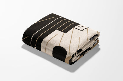 Folded throw blanket with geometric black, beige, and gold stripe pattern.