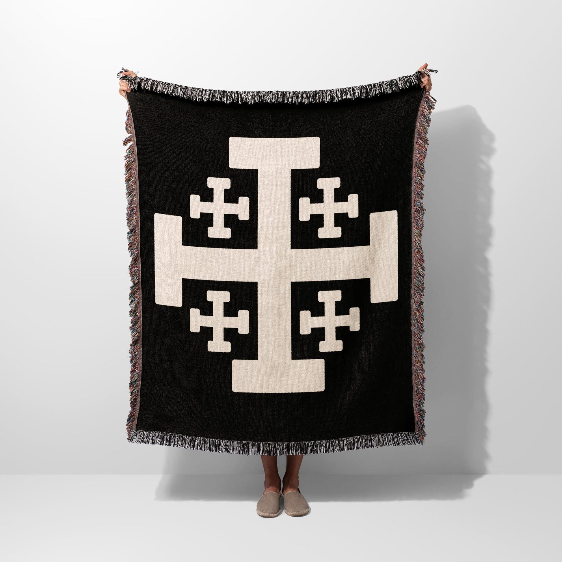 Black throw blanket with large beige Crusader cross and fringed edges.