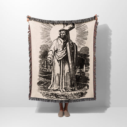 Jesus holding a cross, depicted in a vintage tapestry-style blanket.