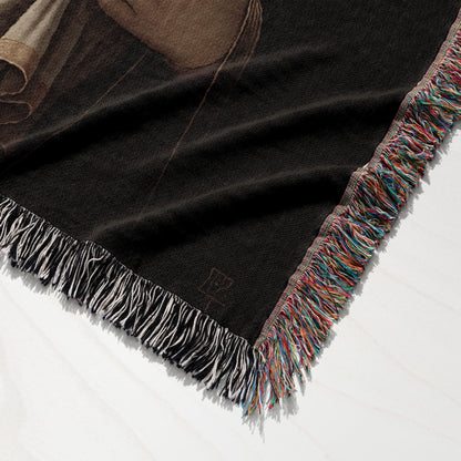 Black woven blanket with fringed edges and a subtle embroidered logo.