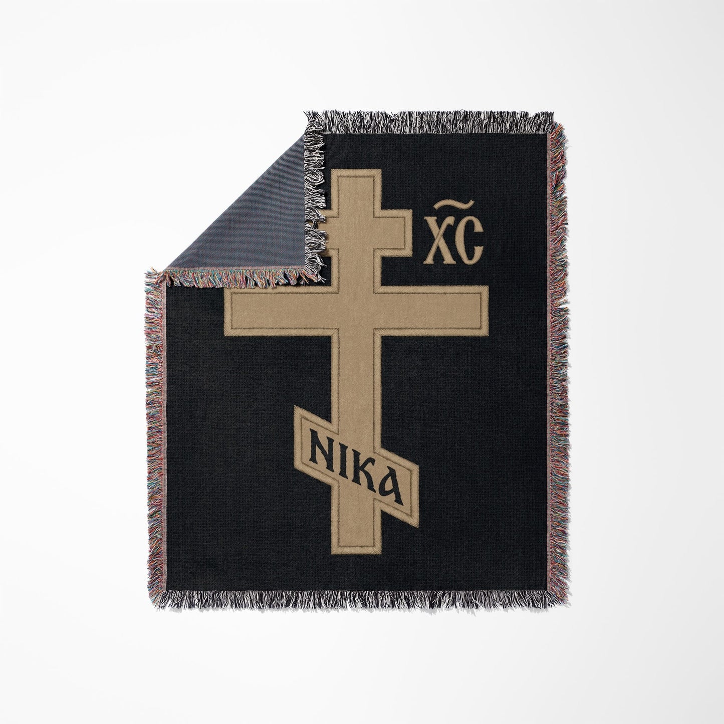 Tan Orthodox cross with "XC NIKA" inscription on black woven blanket.
