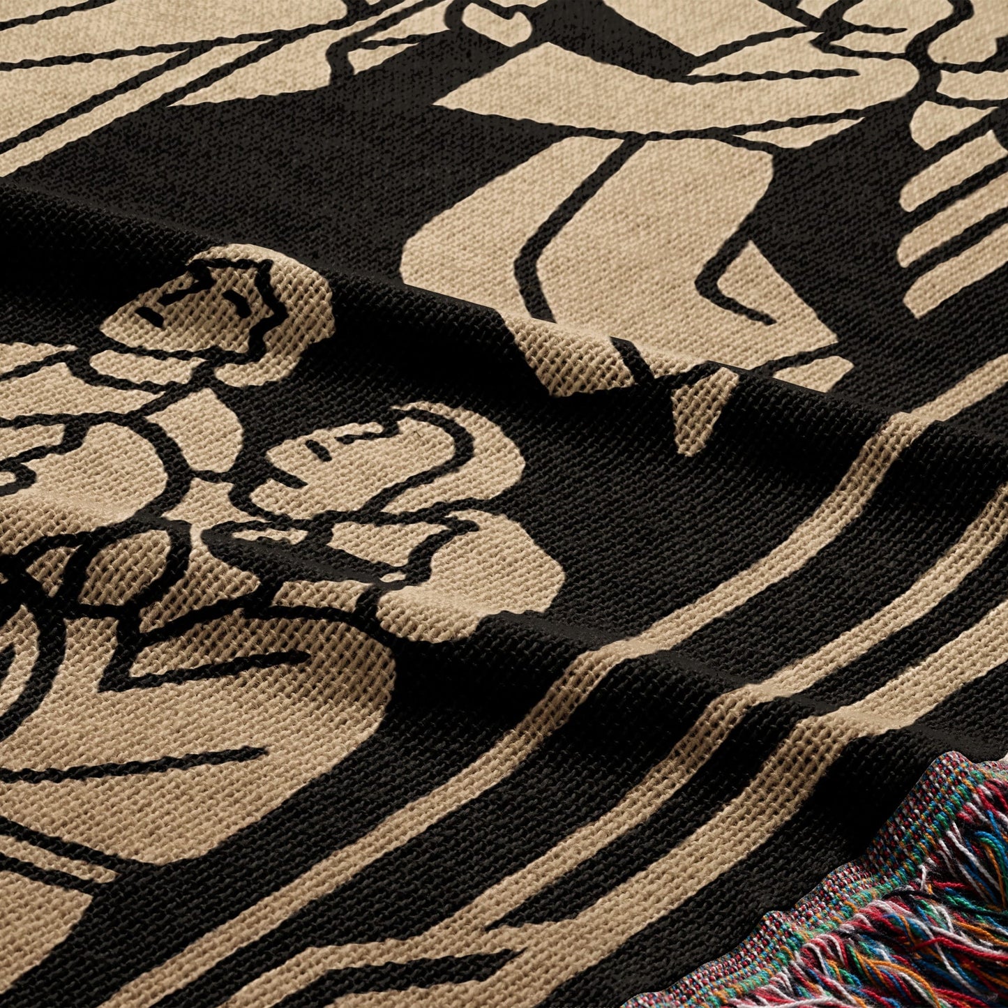 Black and tan woven blanket with floral design and fringed edge.
