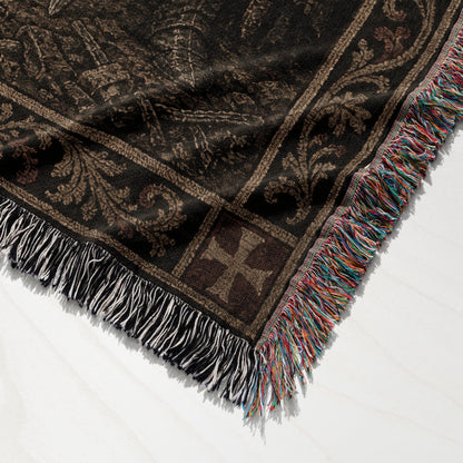Dark woven throw blanket with colorful fringe and a medieval-inspired pattern.