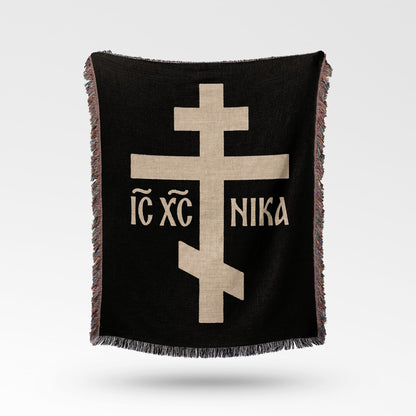 Black throw blanket with beige Eastern Orthodox cross and text.