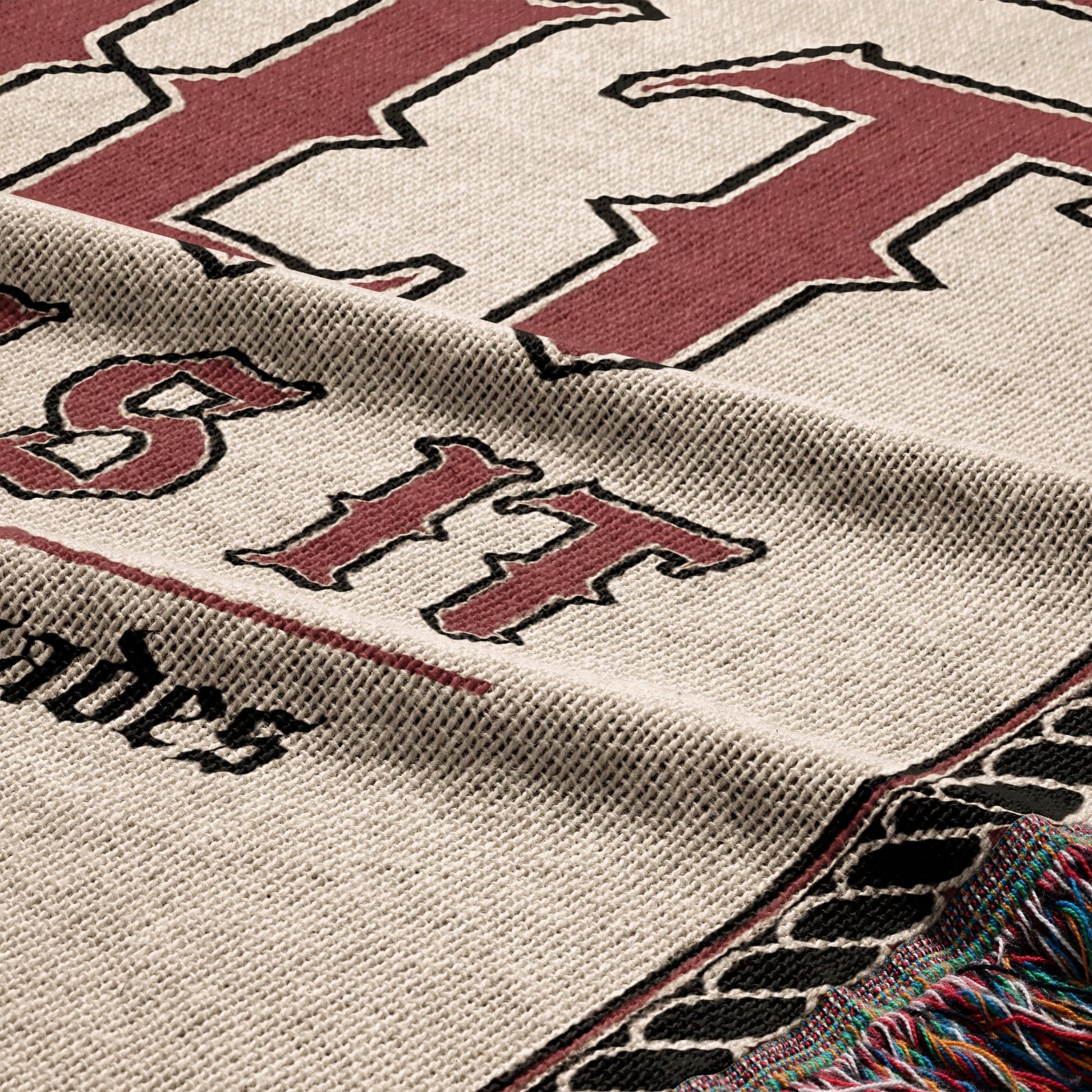 Cream blanket with maroon "BIT" text and tasseled edges.