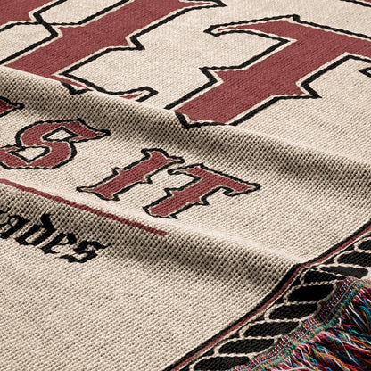 Cream blanket with maroon "BIT" text and tasseled edges.
