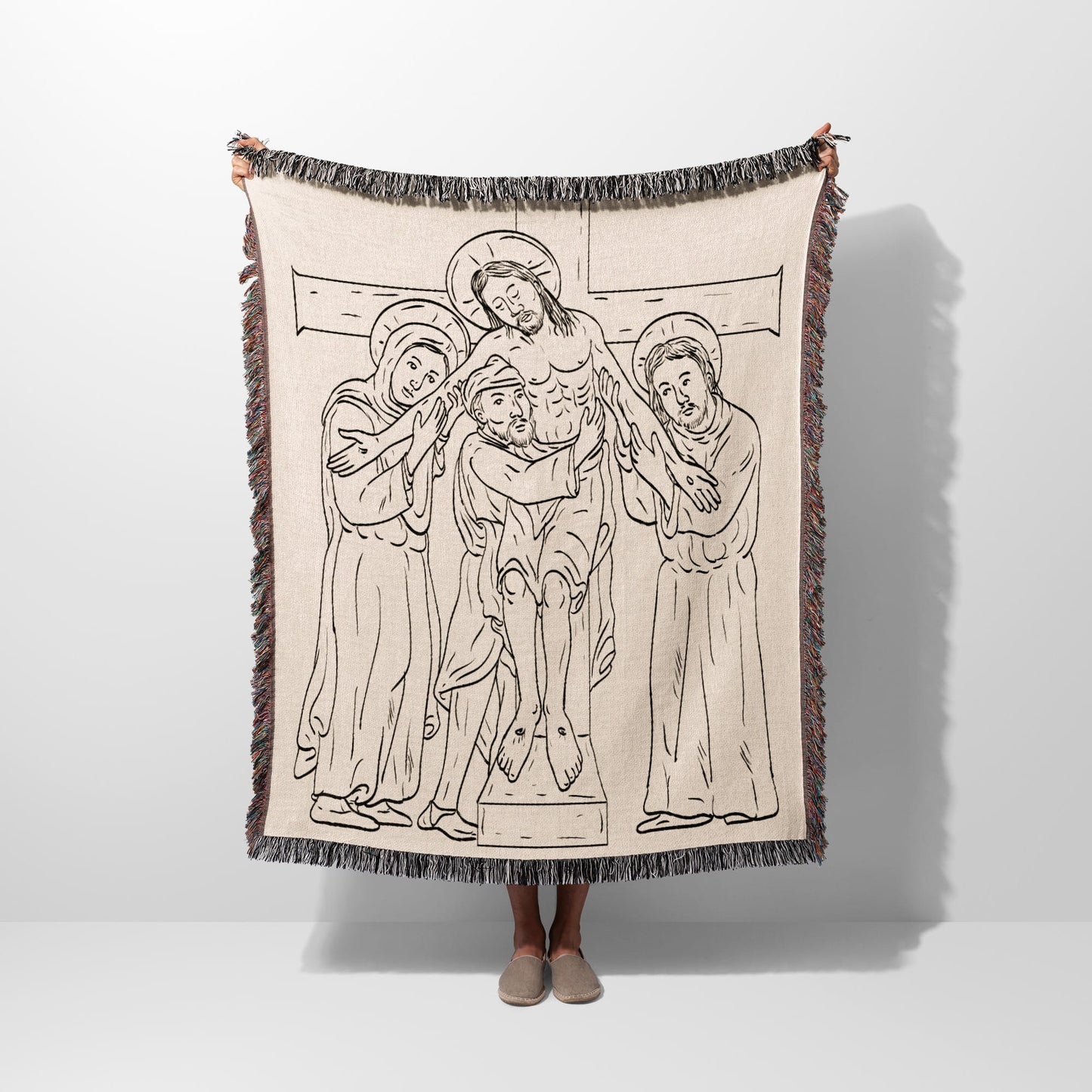 Tapestry blanket with line drawing of Christ's descent from the cross.