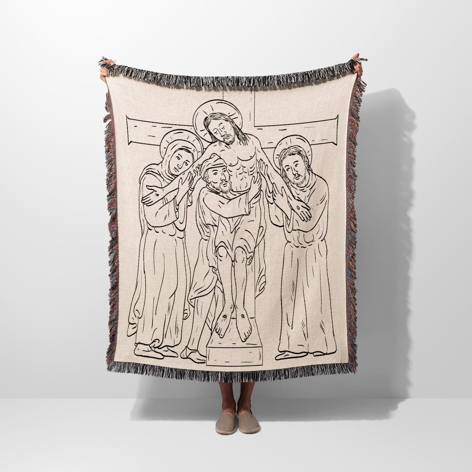 Tapestry blanket with line drawing of Christ's descent from the cross.