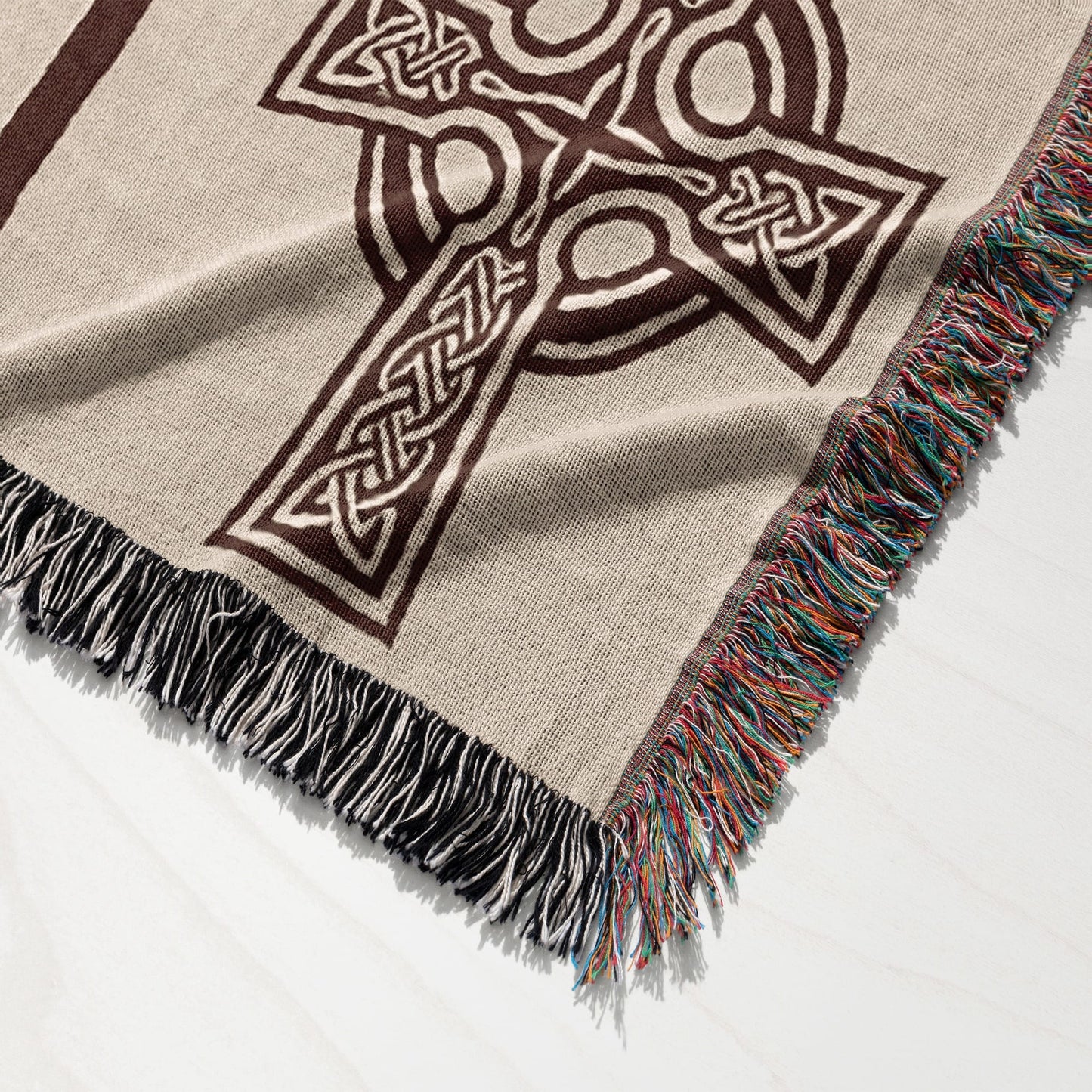 Woven blanket featuring a Celtic cross design with fringed edges.