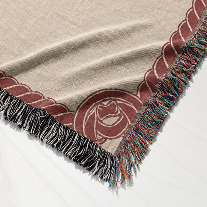 Woven throw blanket with fringed edges and a rose design.