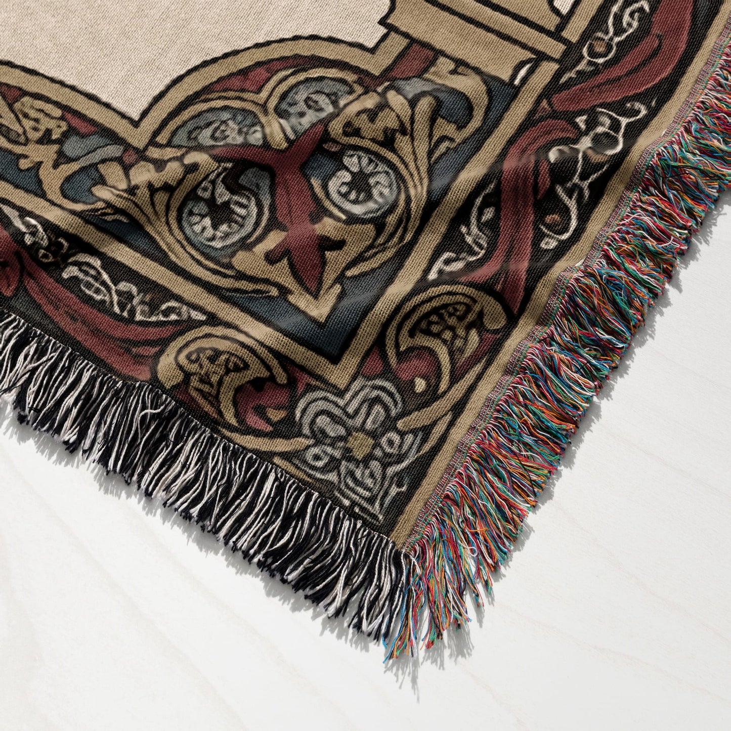 Textured throw blanket with intricate, ornate patterned detail and colorful fringed edges.
