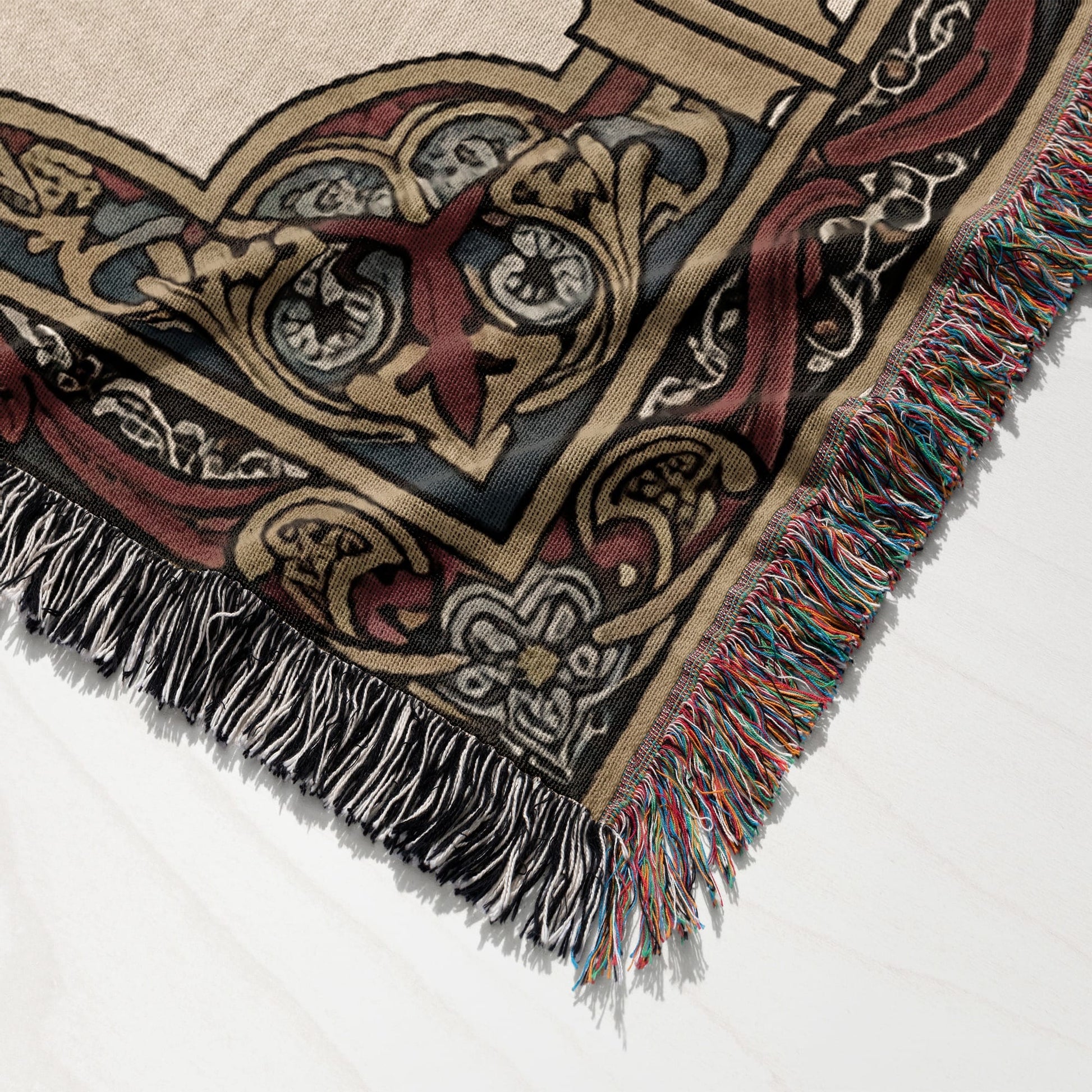 Textured throw blanket with intricate, ornate patterned detail and colorful fringed edges.