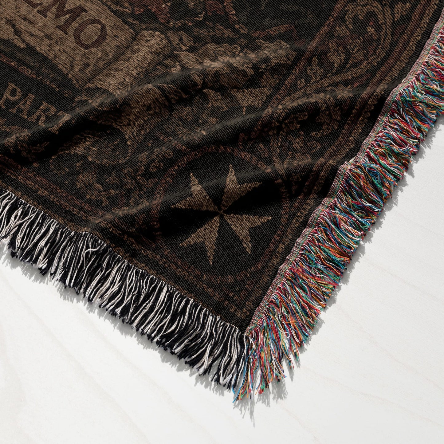 Tapestry with Maltese cross and colorful fringe on white surface.