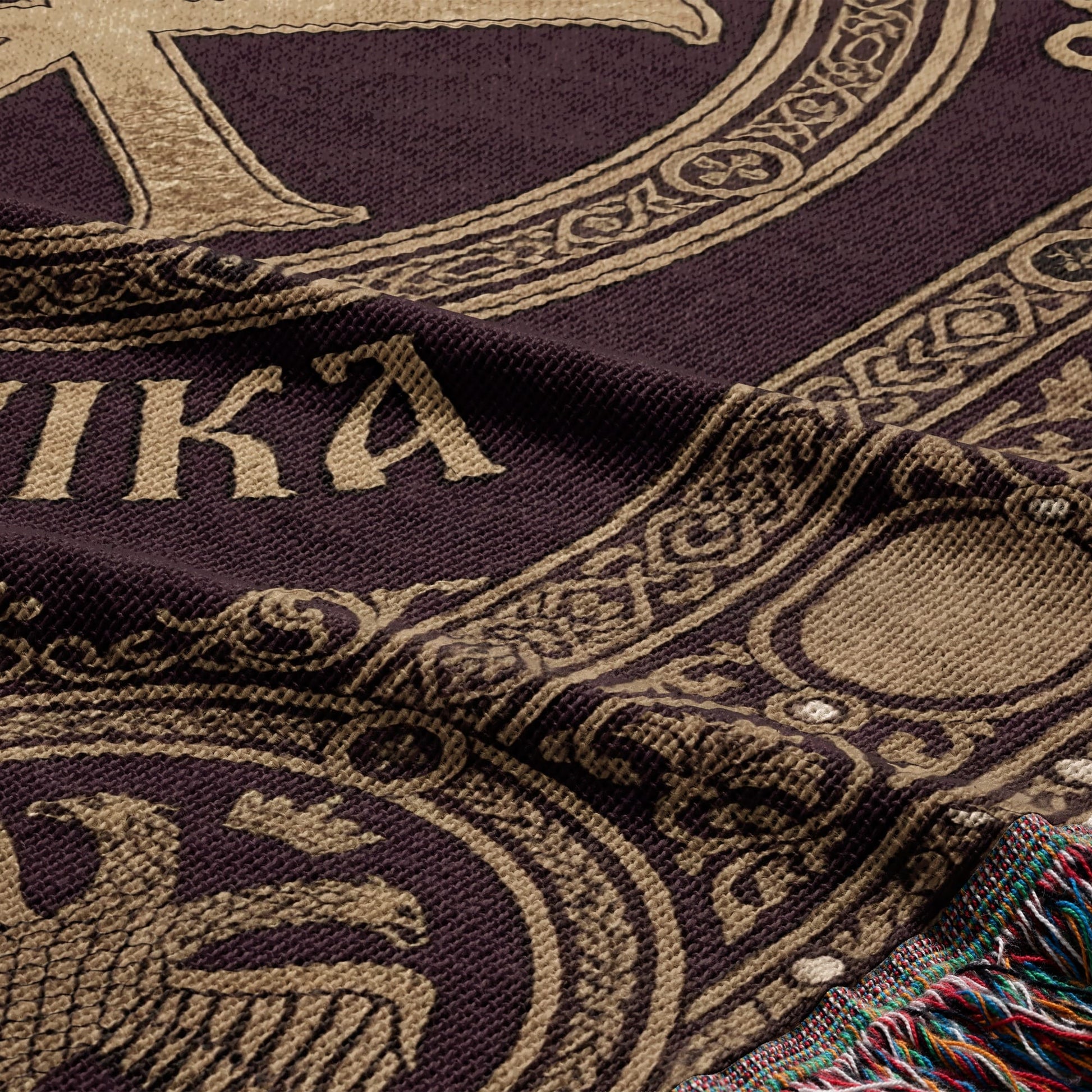 Woven tapestry with "AMIKA" text and ornate border detail, featuring fringed edge.