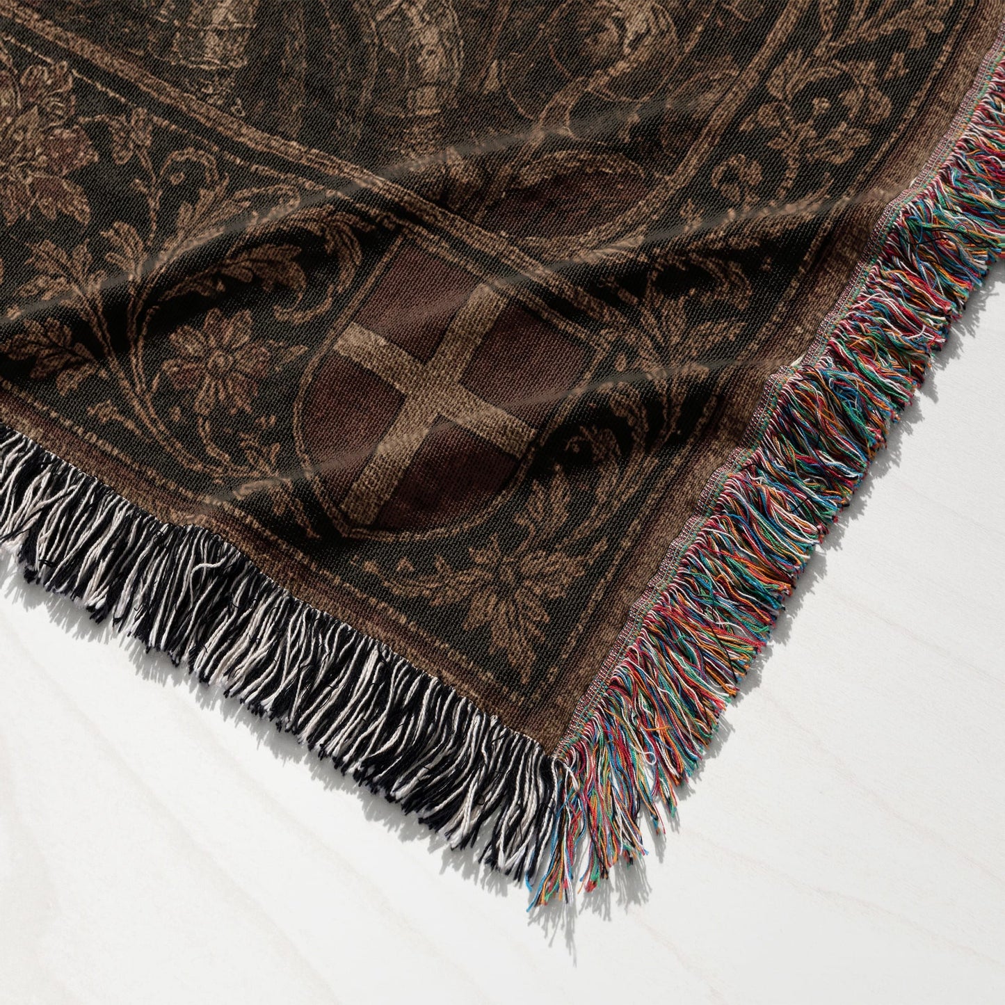 Woven blanket with intricate dark brown pattern and colorful fringed edges.