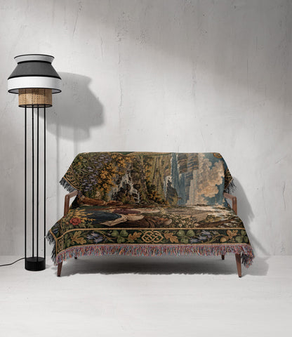 A small wooden sofa draped with a large, intricately patterned woven throw blanket next to a tall floor lamp.