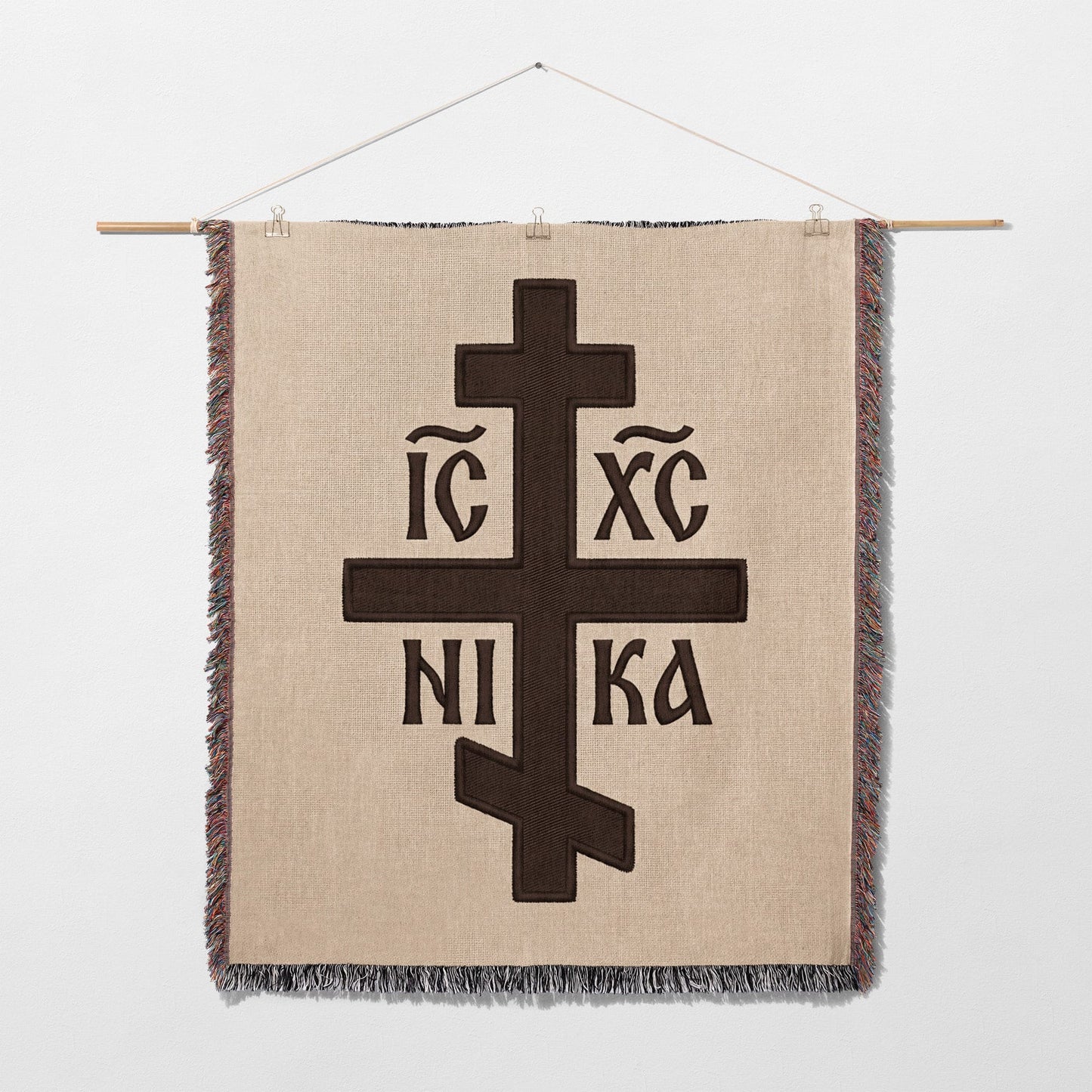 Brown Orthodox cross with Greek lettering on a woven wall hanging.