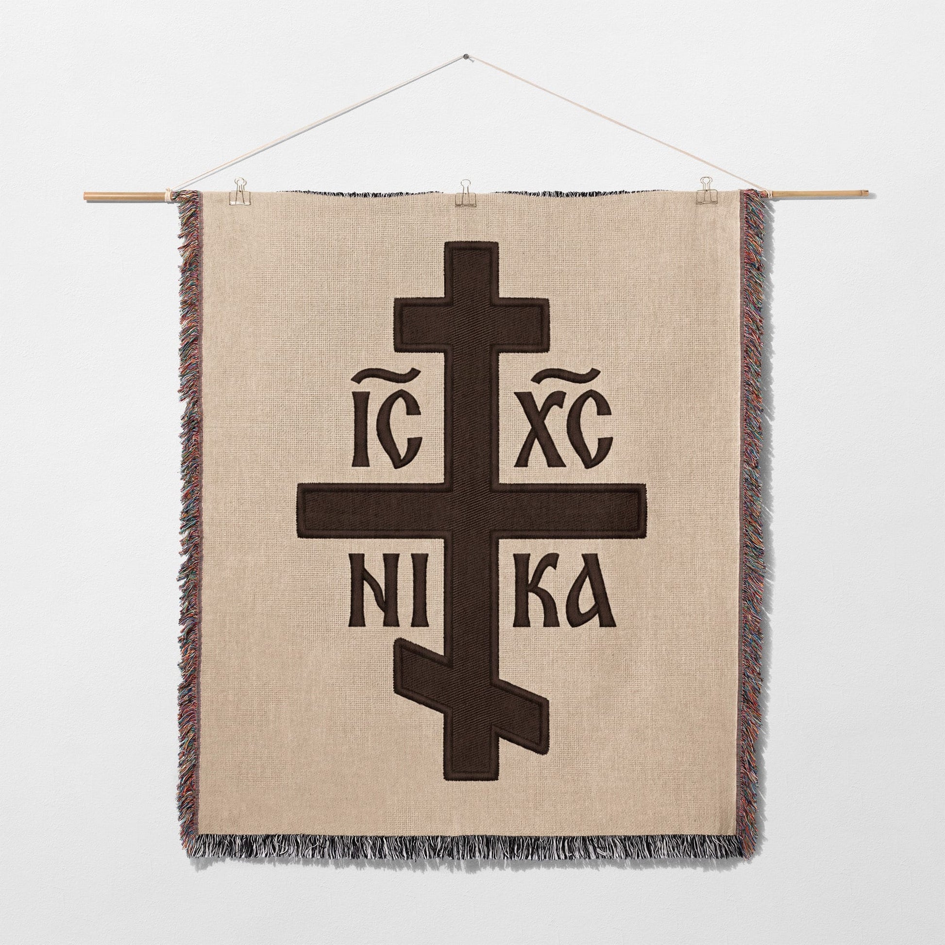Brown Orthodox cross with Greek lettering on a woven wall hanging.