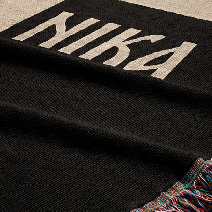 Black woven blanket with white "NIKE" text and a colorful fringed edge.